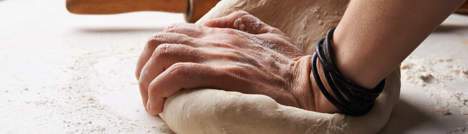 photo de mains entrain de pétrir la pâte à pizza